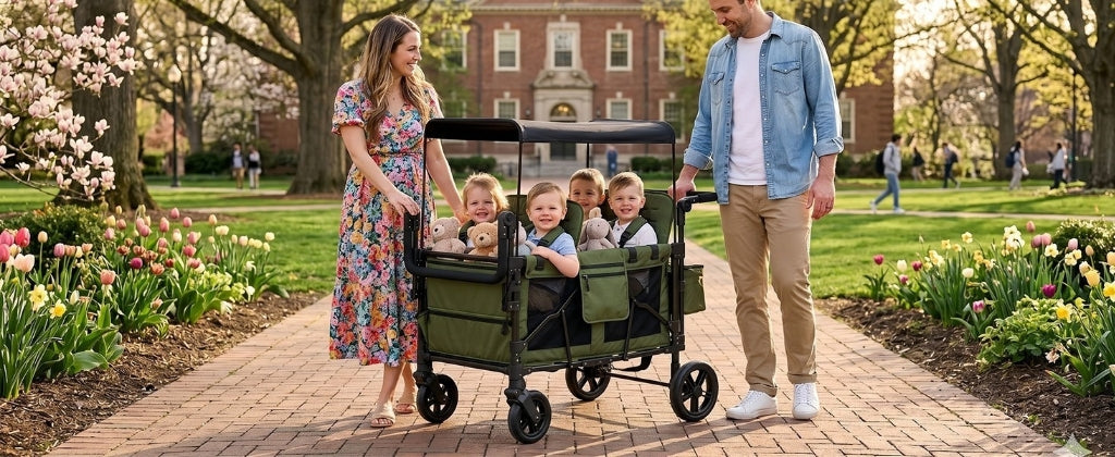 Family with children in a wagon on a park path with blooming flowers and trees.